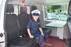 Chłopiec w mundurze podkomisarza policji siedzi w radiowozie